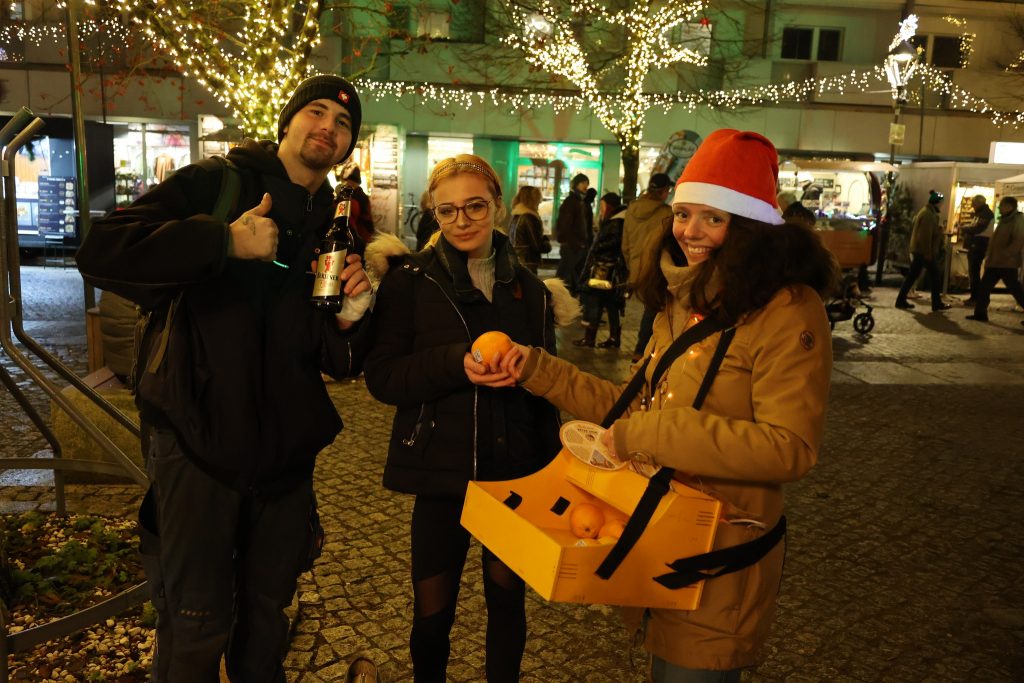 Nadine Schnittke gibt 2 Passanten eine Orange