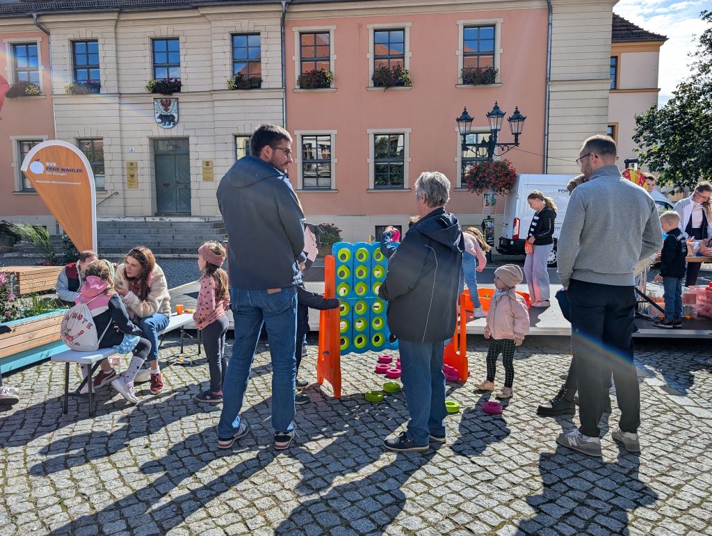Kinder spielen Vier-gewinnt, ein Mädchen wird geschminkt, Erwachsene unterhalten sich
