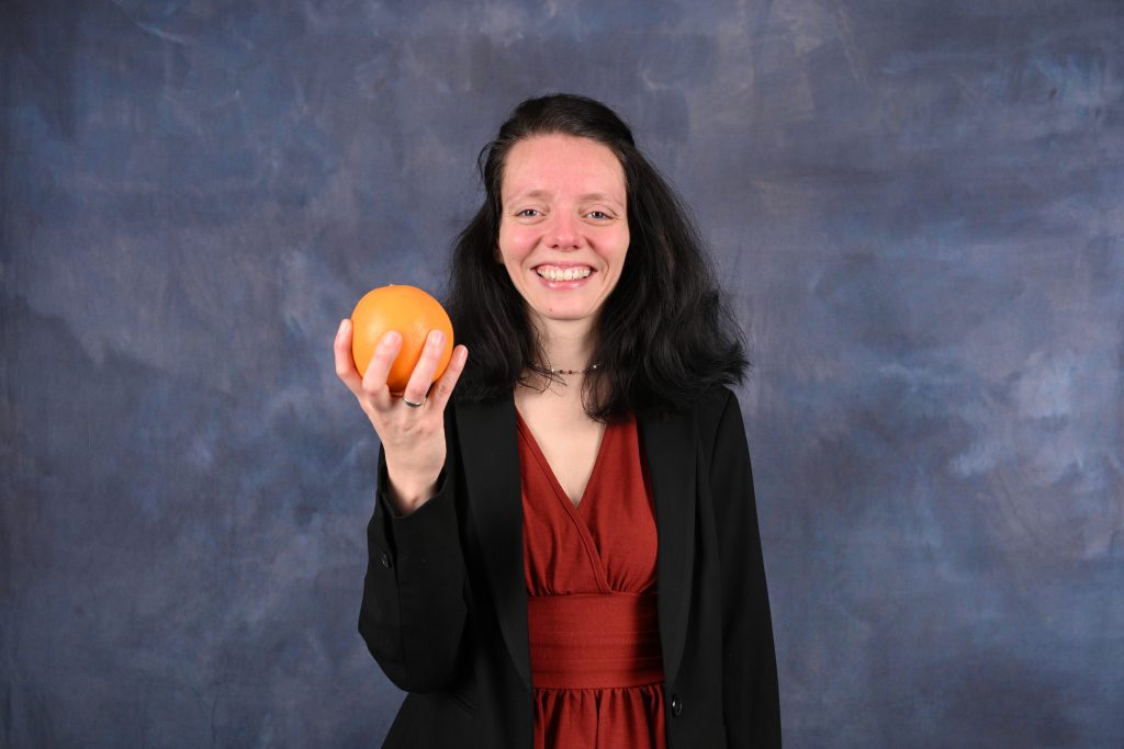 Nadine Schnittke mit Kleid und Blazer, Orange in der Hand