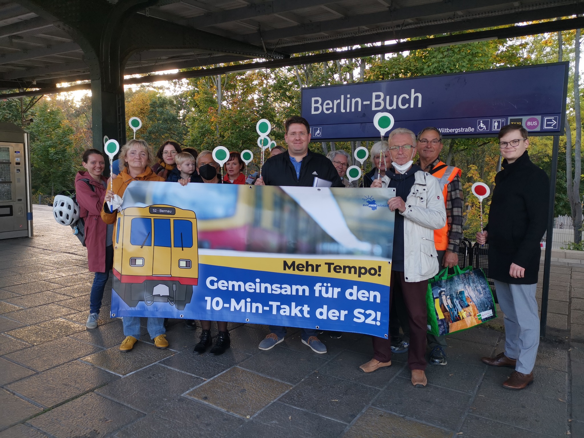 Mehrere Menschen am Bahnhof S Buch mit Banner
