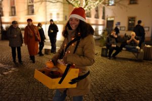 Nadine Schnittke mit Weihnachtsmütze und Bauchladen Orangen verteilen auf dem Bernauer Weihnachtsmarkt