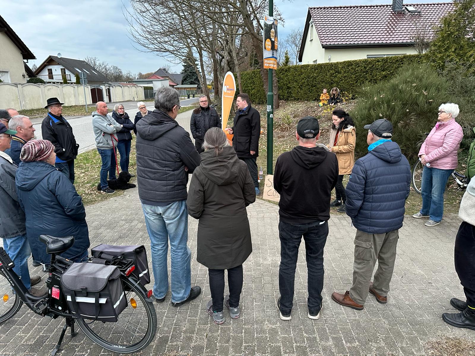 Nadine Schnittke und eine Traube von Menschen um Péter Vida im Blumenhag