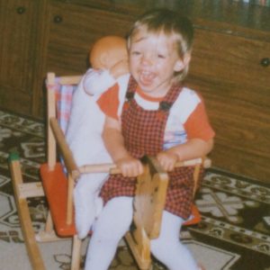 Nadine auf Schaukelpferd mit Puppe ca. 3 Jahre alt
