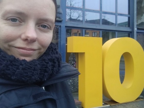 Nadine Schnittke neben großem Aufsteller mit einer 10 am Bahnhof